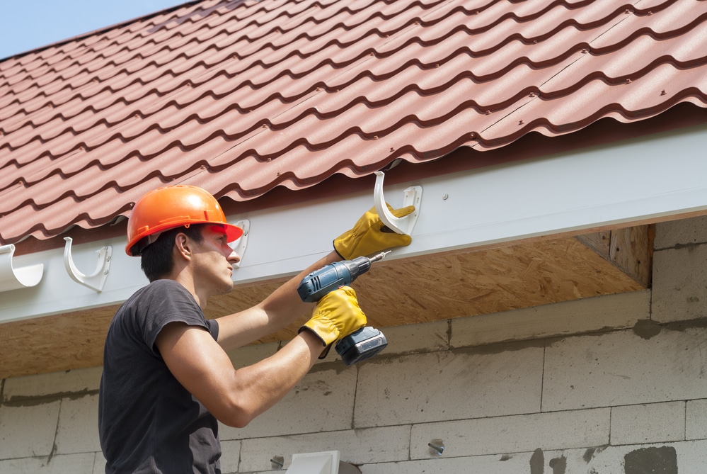 worker installs the gutter system on the roof