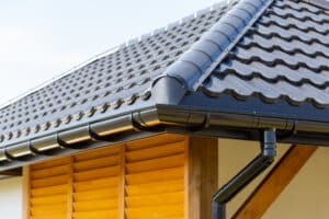Corner of the house with steel roof and gutter and wooden shutter